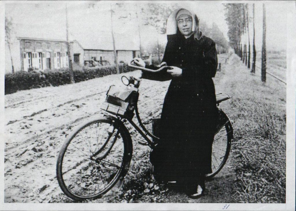 Zuster op fiets bij klooster Malden rijksweg